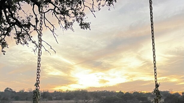 Two people sitting on a swing in an open field with a sunset in the background. - The Ranch@Fredericksburg - The Blue Bonnet - 2BD/2BA (Fredericksburg)