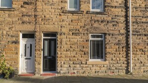 A stone building with three windows, a door, and a satellite dish. - 55 Wellwood Street (Morpeth)