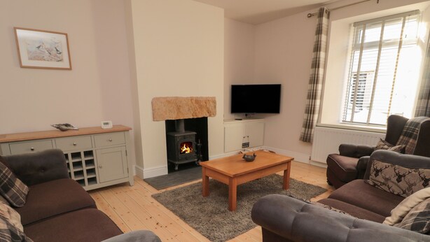 A cozy living room with a fireplace, a television, and comfortable seating. - 55 Wellwood Street (Morpeth)