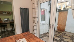 A wooden table with a notebook in a room with a sliding glass door leading to an outdoor area with a tiled patio. - 55 Wellwood Street (Morpeth)