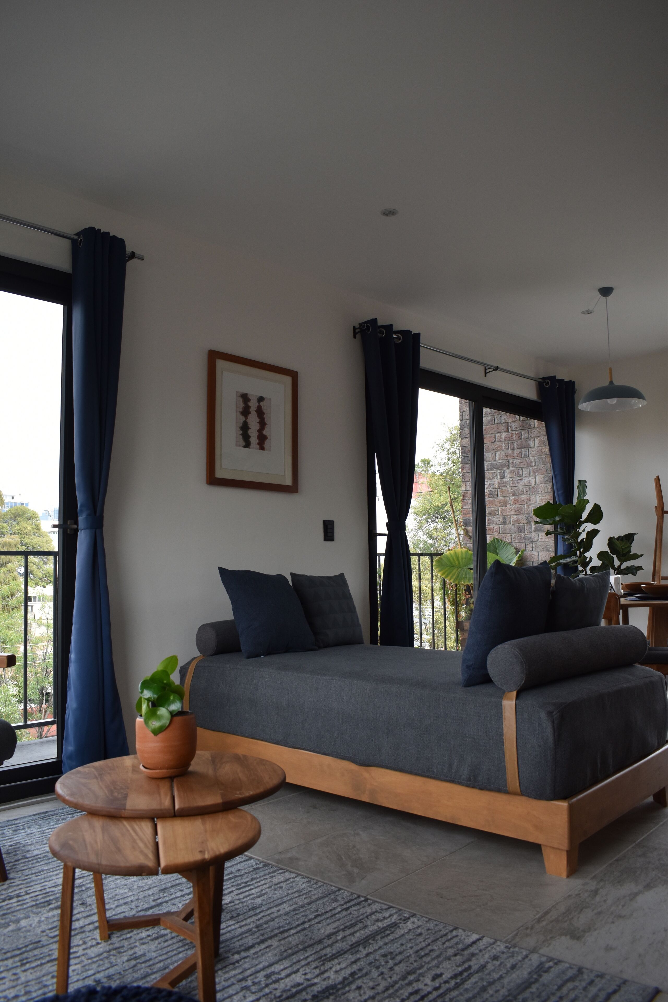 Une chambre à coucher moderne avec un lit, une petite table en bois et une plante en pot.