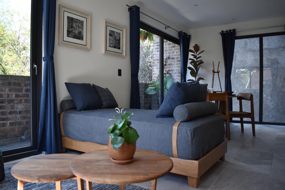 A modern room with a large bed, two framed pictures, a potted plant, and a wooden chair.
