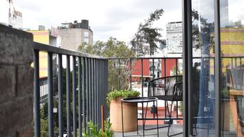 A balcony with a table and chairs, potted plants, and a view of the cityscape.