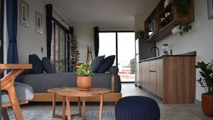 A modern living room with a sofa, a round wooden table, and a blue pouf. - Apartments Art Tanat (Mexico City)