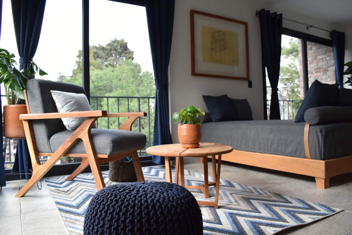 A modern living room with a sofa, a chair, a small table, and a potted plant.