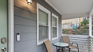 A porch with a glass table and two chairs, a door with a keypad lock, and a window with a white frame. - Luxe Modern 3BR Sleeps 6 by Atlantic Station (Atlanta)