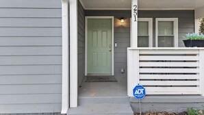 A house with a green door, white front porch, and a blue sign with 'ADT' on it. - Luxe Modern 3BR Sleeps 6 by Atlantic Station (Atlanta)