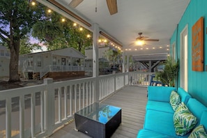 A covered outdoor area with a white railing, a blue sofa, and string lights. - Open concept, w/Covered Porch + Golf Cart (Myrtle Beach)