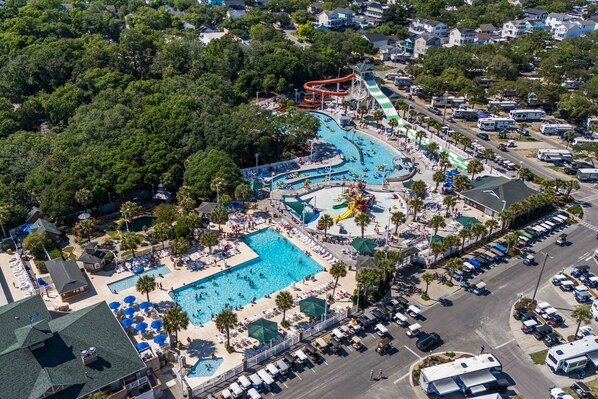 An aerial view of a resort with multiple swimming pools, a water park, and RV parking.