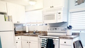 A kitchen with white cabinets, a microwave, an oven, and a sink.
