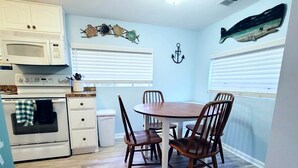 A kitchen with white cabinets, a microwave, an oven, and a dining table with four chairs.