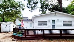 A single-story mobile home with a front porch, a small attached garage, and a fenced yard.