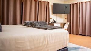 Habitación de hotel con una cama grande, un televisor de pantalla plana en la pared y un escritorio con una silla.