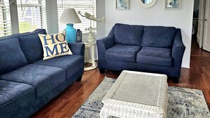 A living room with two dark blue sofas, a white coffee table, and a patterned rug.