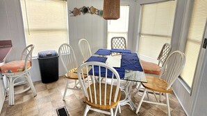 A dining area with a table set for four, surrounded by white chairs with wooden seats.