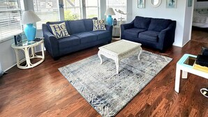 A living room with two dark blue sofas, a white coffee table, a patterned rug, and a ceiling fan.