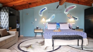 Une chambre à coucher avec un lit, des tables de chevet, un banc, une commode et une porte.