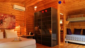 Una habitación tipo cabaña de madera con cama, armario empotrado y literas.