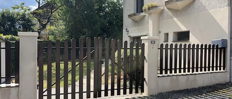 A gated property with a paved driveway, a mailbox, and a number sign indicating the address.