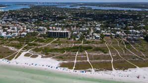 Vue aérienne d’une ville côtière avec une plage, des immeubles résidentiels et un grand hôtel.