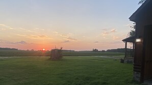 A rural landscape with a sunset, open fields, and a wooden cabin. - Newly added studio apartment, above garage.  (Marvell)