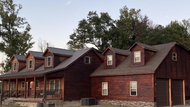A row of log cabins with a stone foundation, a covered porch, and a gravel driveway. - Newly added studio apartment, above garage.  (Marvell)
