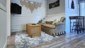 Una sala de estar acogedora con un sofá, una mesa de centro de madera y un tapiz tejido en la pared.