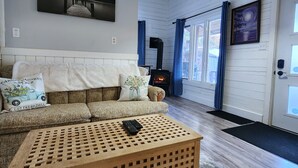 Una sala de estar acogedora con sofá, una mesita de madera, chimenea y una lámpara de techo.