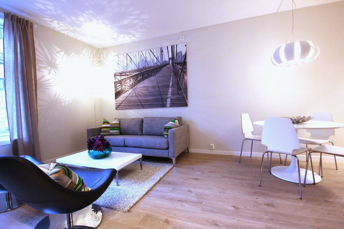 A modern living room with a sofa, coffee table, and a dining area with chairs and a table.