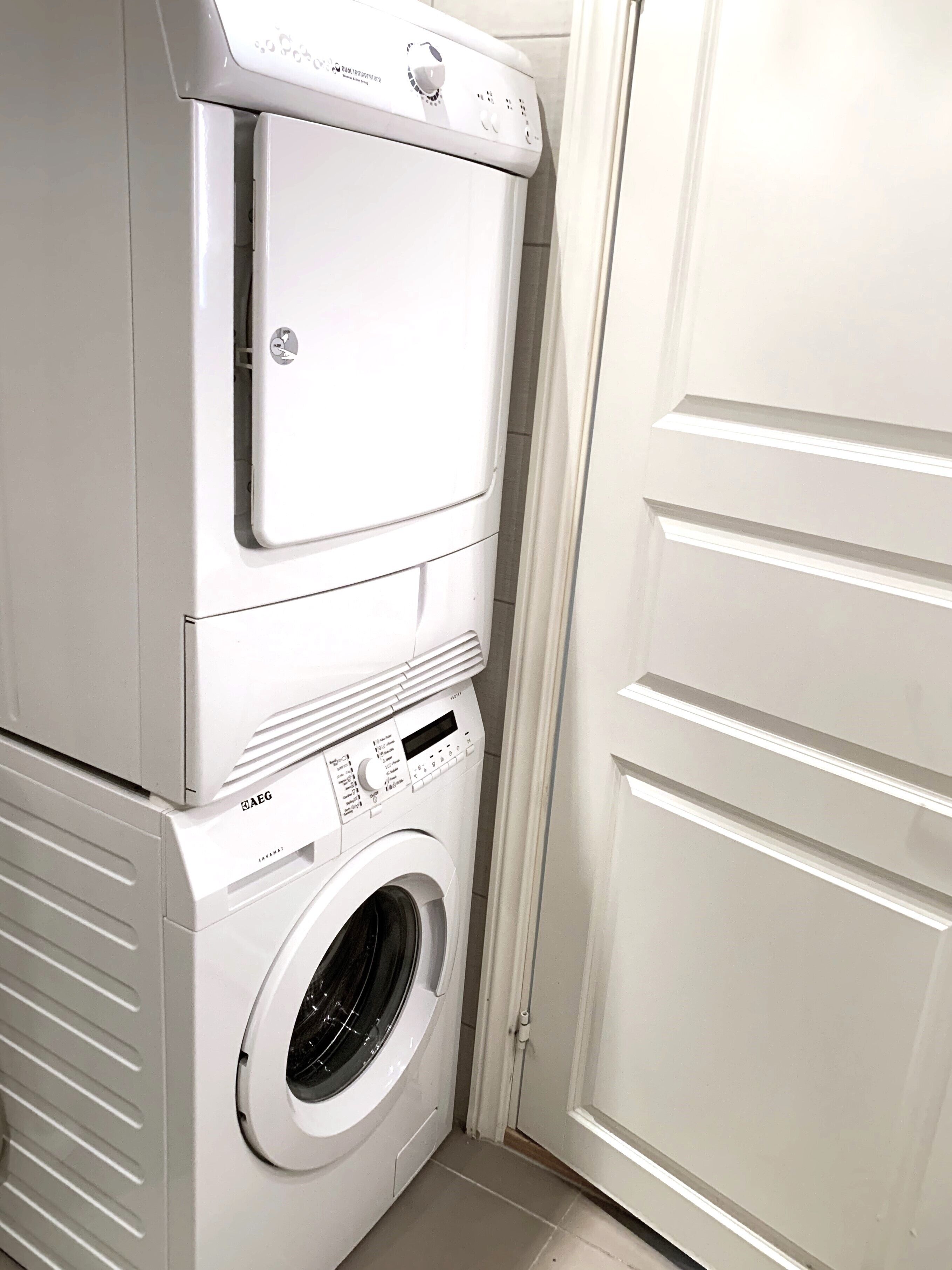 Une machine à laver et un sèche-linge superposés, placés dans un coin de la pièce.