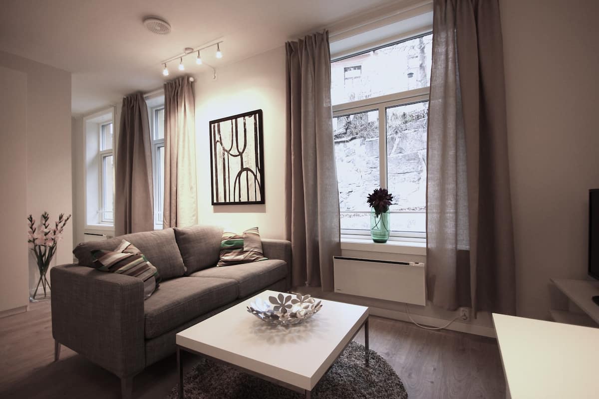 A modern living room with a sofa, a coffee table, and a window with curtains.