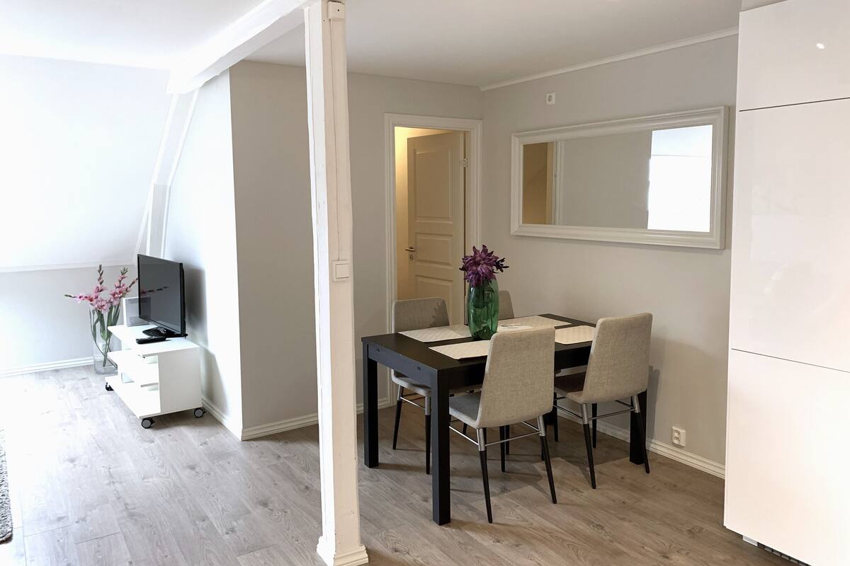 A modern dining area with a table, chairs, and a vase of flowers.
