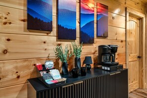 A wooden cabin interior with a reception desk, coffee maker, and framed landscape paintings. - RIVERFRONT Escape - Fishing/SwimmingHole/HotTub/Firepit/Games/Private/Near GSMNP (Sevierville)