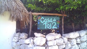 A rustic wooden sign with the text "Casa de Toj2" and a colorful bird decoration. - Casa de Toj2 (Chicxulub Pueblo)