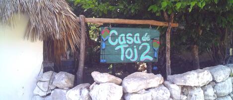 A rustic wooden sign with the text "Casa de Toj2" and a colorful bird decoration.