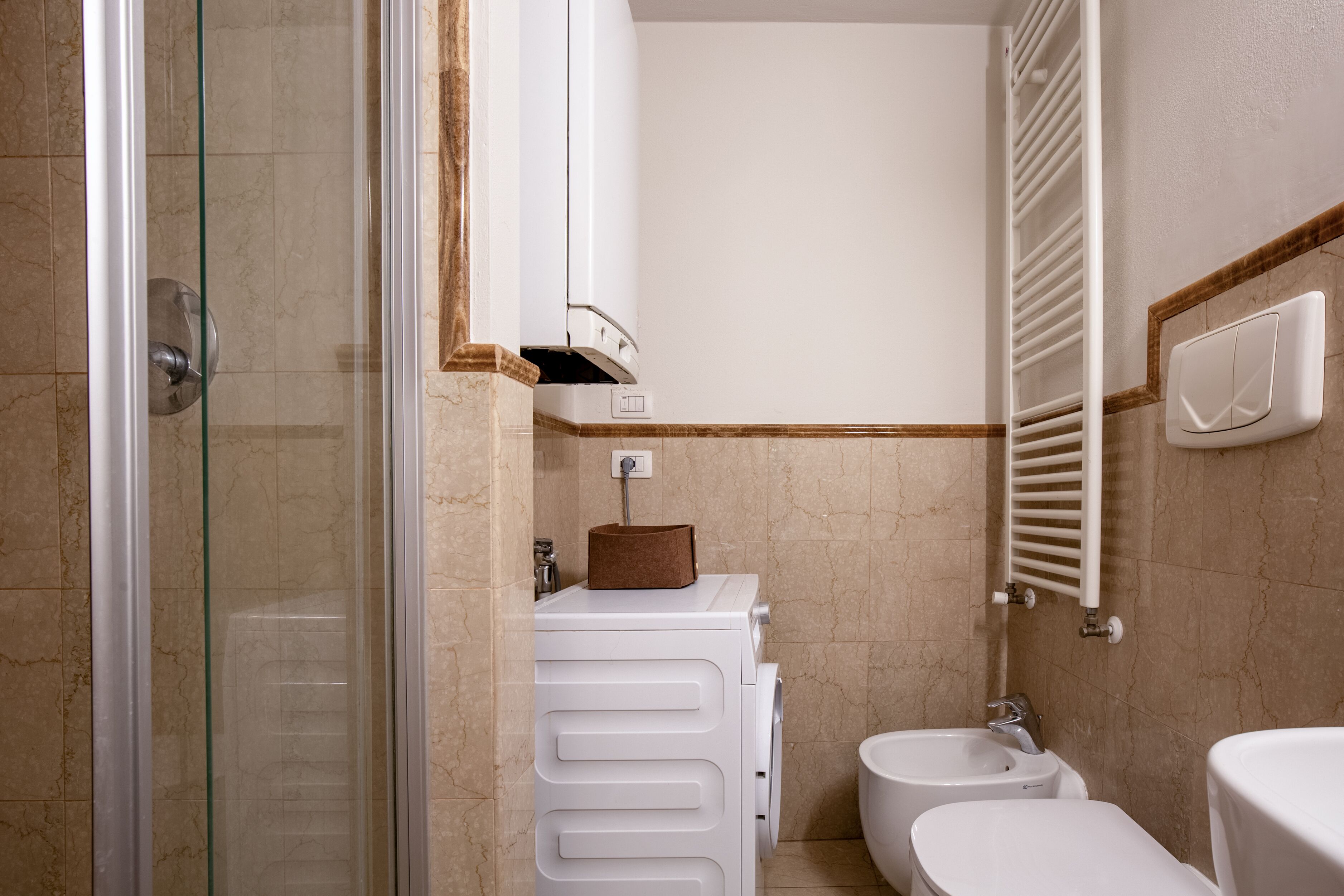 Une salle de bain avec une douche à parois de verre, des toilettes blanches, un bidet et un porte-serviettes.