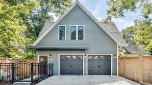 A two-story house with a grey exterior, a front porch, and a driveway leading to a garage with two doors.