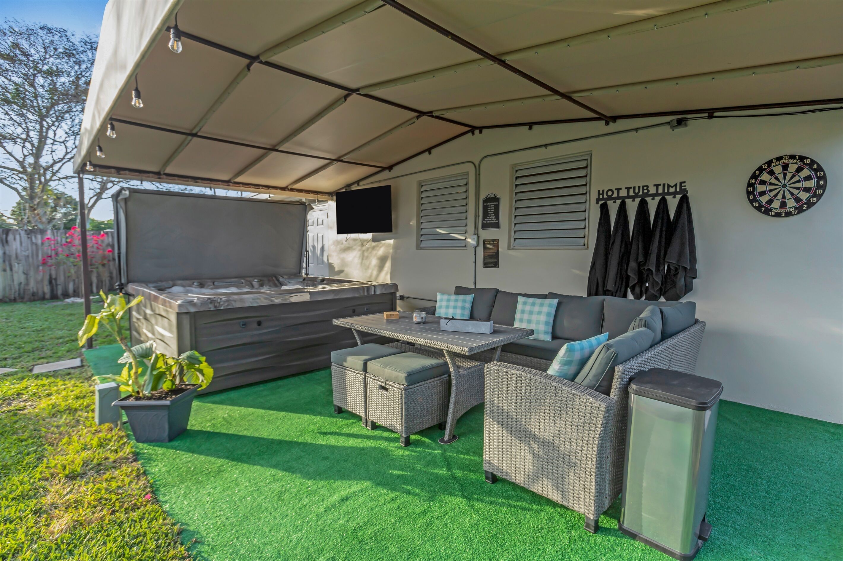 Un patio exterior con zona de estar cubierta, jacuzzi y dardos.