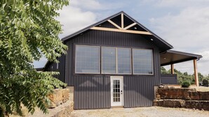 Un bâtiment moderne à l’extérieur sombre, doté de grandes fenêtres et d’une fondation en pierre.