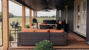 Un espace extérieur aménagé avec des meubles en osier, un barbecue et une vue sur la campagne.