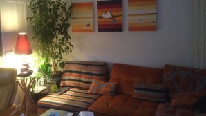 A living room with a sofa, a lamp, and a potted plant.