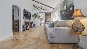A spacious living area with a grey sofa, a decorative lamp, and a large painting on the wall.