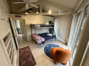 Cozy room with a bunk bed setup, ceiling fan, and large window with blinds.