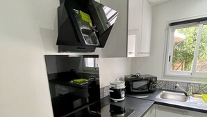 A modern kitchen with a black stove, microwave, and black range hood. There is a window with a view of greenery outside.