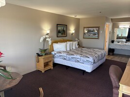 Una habitación de hotel con cama, mesita de noche, lámpara y un cuadro en la pared.
