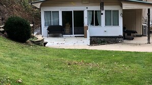 Ein zweistöckiges Haus mit überdachter Terrasse, Schornstein und kleiner angeschlossener Garage.