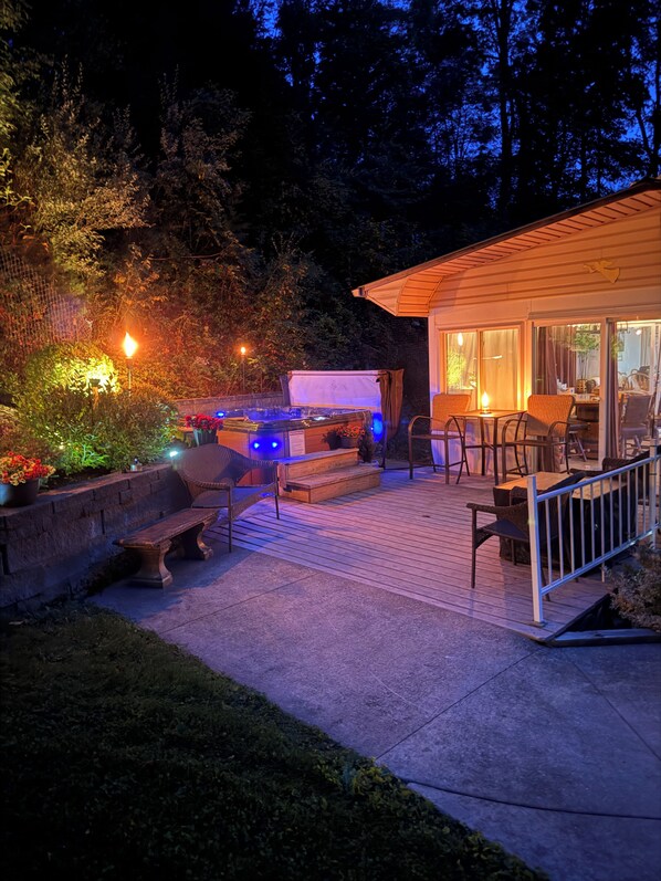 A patio area with outdoor seating, a hot tub, and a building with large windows.