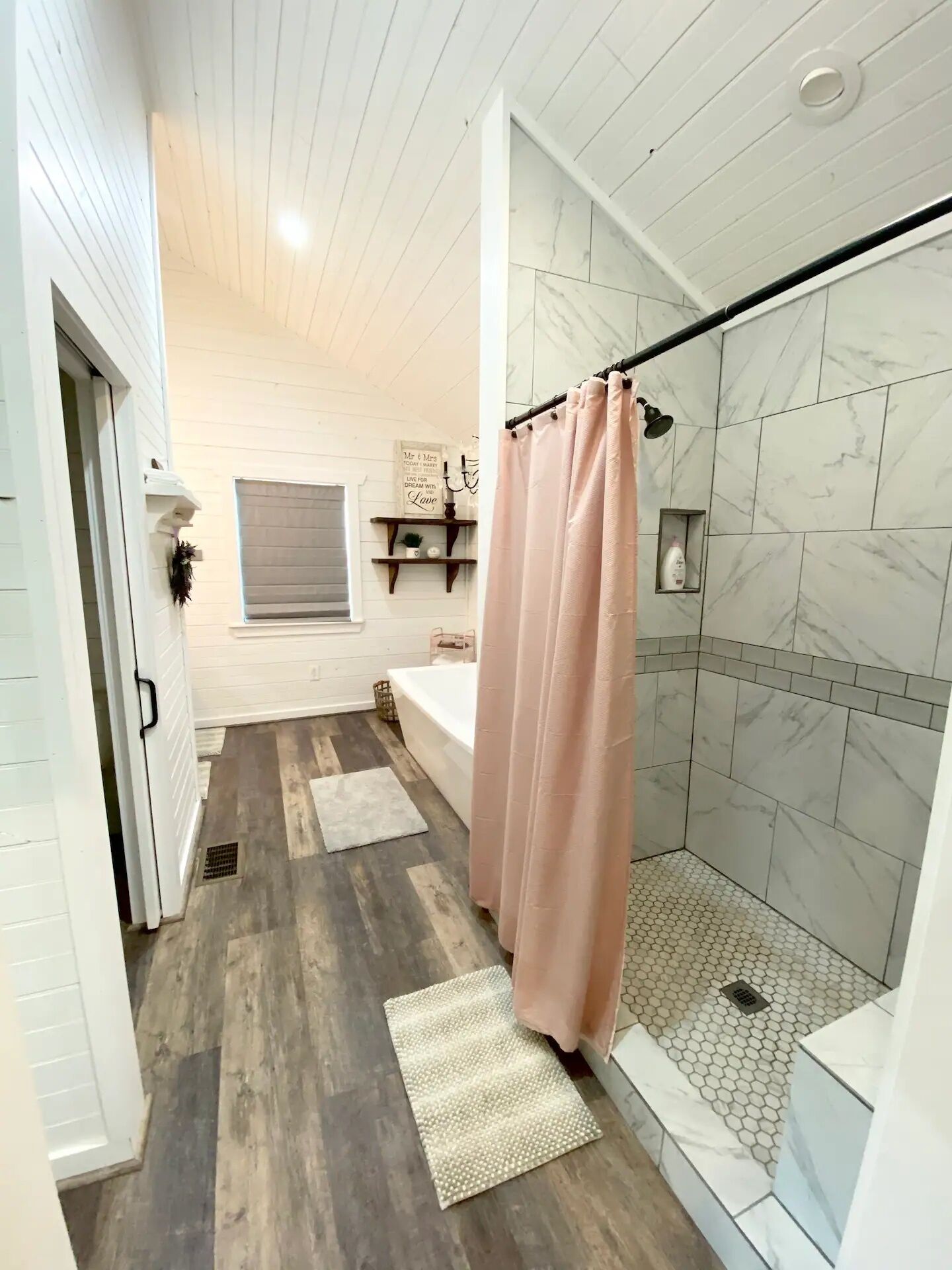Et badeværelse med bruser, badekar og toilet.