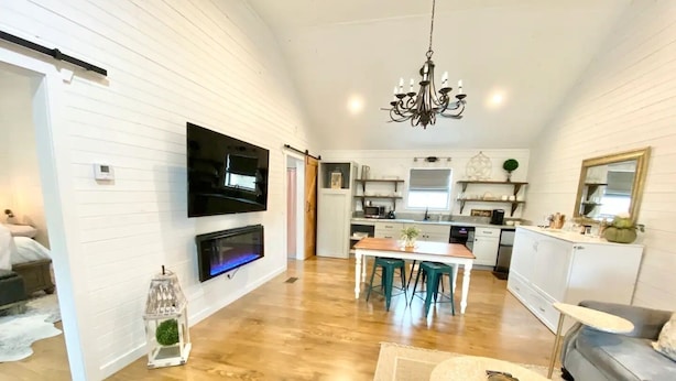 A spacious living room with a TV, fireplace, and a dining area with stools. - The Ranch@Fredericksburg - Magnolia Cottage - 1BD/1BA (Fredericksburg)