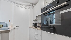 A compact kitchen with white cabinets, a black refrigerator, and a window above the sink.